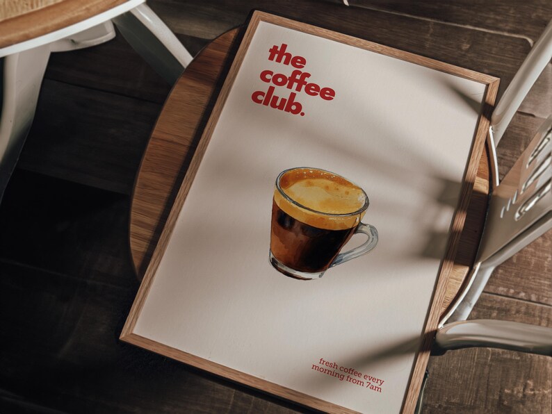 Puede incluir: Un p&oacute;ster enmarcado con una ilustraci&oacute;n de acuarela de una taza de caf&eacute;. El p&oacute;ster tiene el texto "the coffee club." y "fresh coffee every morning from 7am" en rojo.