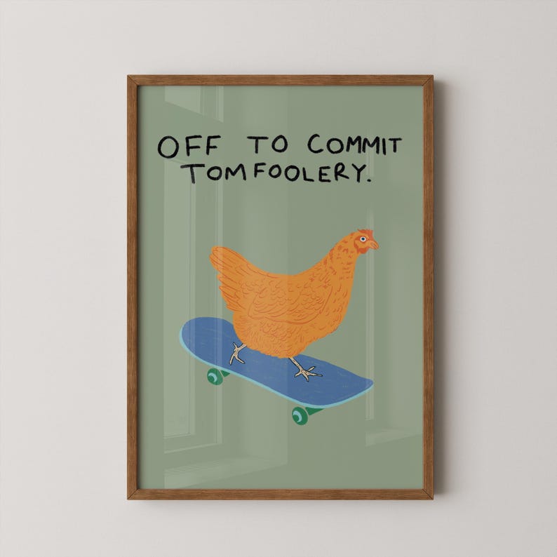 May include: A framed art print featuring a cartoon chicken riding a blue skateboard. The chicken is orange, and the skateboard has green wheels. The text at the top reads, "OFF TO COMMIT TOMFOOLERY."