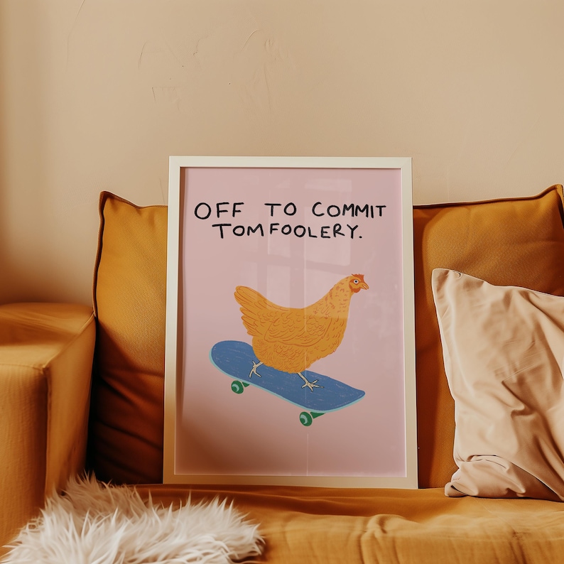 May include: A framed art print featuring a whimsical illustration of a chicken riding a blue skateboard. The chicken is orange and the skateboard has green wheels. The text at the top reads "OFF TO COMMIT TOM FOOLERY."