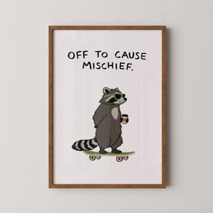 Puede incluir: Impresi&oacute;n enmarcada con un mapache de dibujos animados con gafas de sol y una taza de caf&eacute;, montado en una patineta. El texto "OFF TO CAUSE MISCHIEF" est&aacute; encima del mapache. Fondo blanco, marco marr&oacute;n.