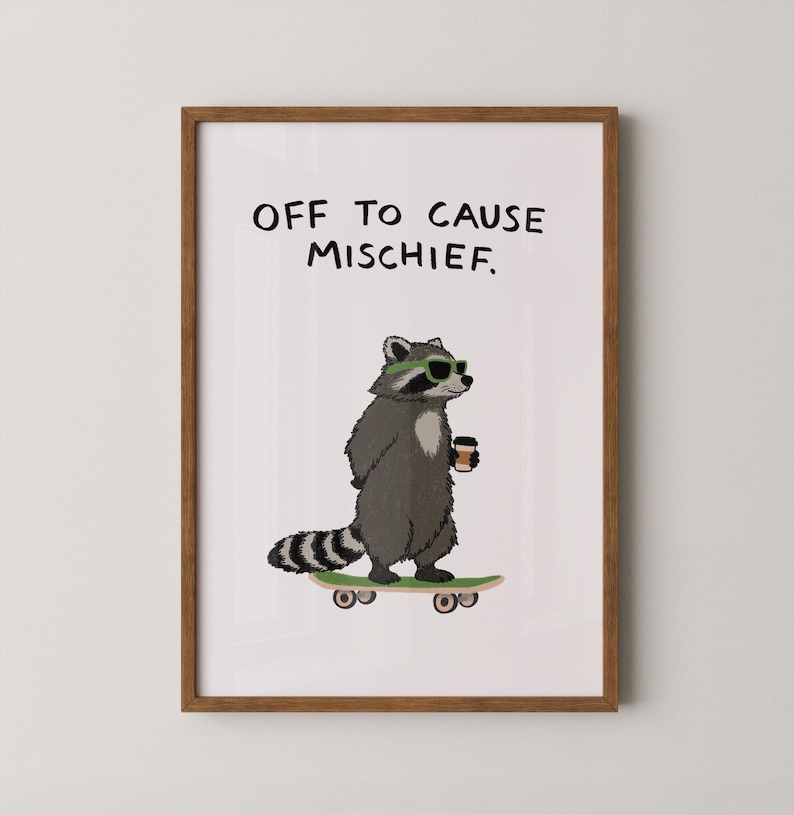 Puede incluir: Impresi&oacute;n enmarcada con un mapache de dibujos animados con gafas de sol y una taza de caf&eacute;, montado en una patineta. El texto "OFF TO CAUSE MISCHIEF" est&aacute; encima del mapache. Fondo blanco, marco marr&oacute;n.