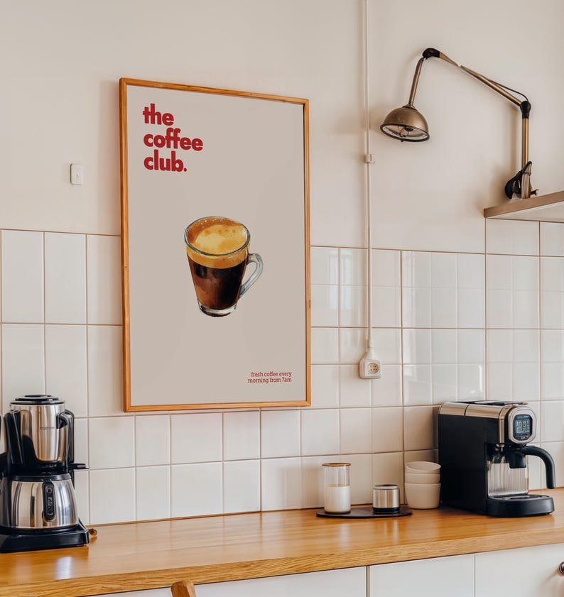 Puede incluir: Un p&oacute;ster enmarcado con un dise&ntilde;o minimalista que presenta una taza de caf&eacute; con espuma marr&oacute;n y blanca. El p&oacute;ster tiene el texto "the coffee club." y "fresh coffee every morning from 7am" en rojo.