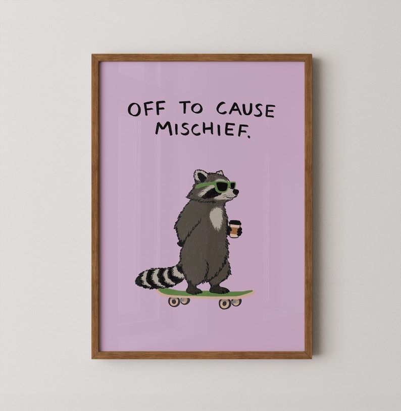 Puede incluir: Una impresi&oacute;n enmarcada con un mapache de dibujos animados con gafas de sol y sosteniendo una taza de caf&eacute;, de pie sobre una patineta. La impresi&oacute;n tiene el texto "OFF TO CAUSE MISCHIEF" sobre un fondo lavanda. El marco es marr&oacute;n.