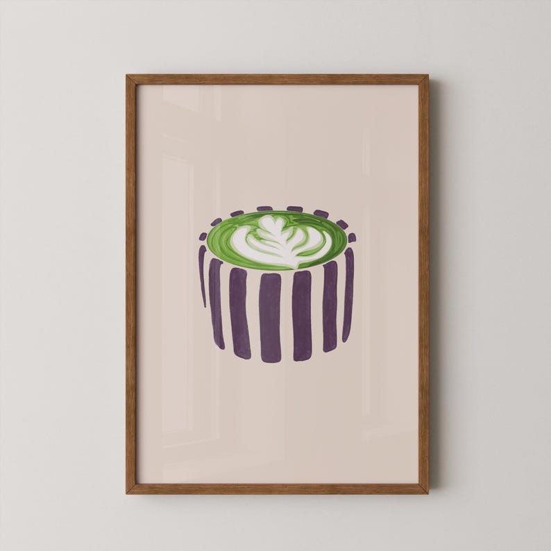 May include: A framed art print featuring a stylized illustration of a matcha latte. The drink is in a purple and white striped cup, topped with green foam and white latte art. The frame is a warm brown color.