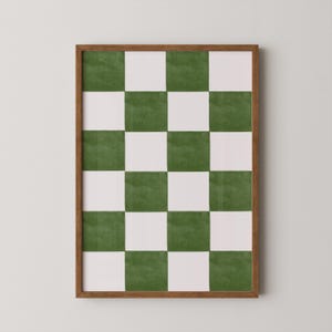 May include: A framed artwork featuring a checkerboard pattern in green and white. The artwork is encased in a brown wooden frame. The green squares have a watercolor-like texture, adding depth to the design. The overall aesthetic is modern and minimalist.
