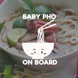 May include: A white cartoon bowl with a face and chopsticks holding noodles. The text "BABY PHO ON BOARD" is below the bowl. The bowl is in front of a blurry image of a bowl of pho.