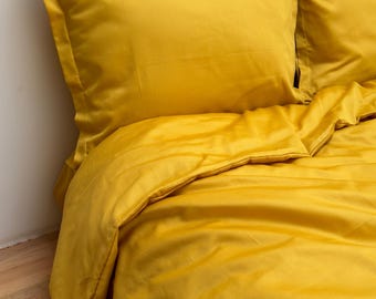 May include: A mustard yellow duvet cover and two matching pillowcases. The bedding is made of a soft, smooth fabric and has a subtle sheen.