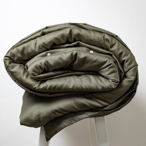 May include: A rolled up olive green duvet cover with white buttons.