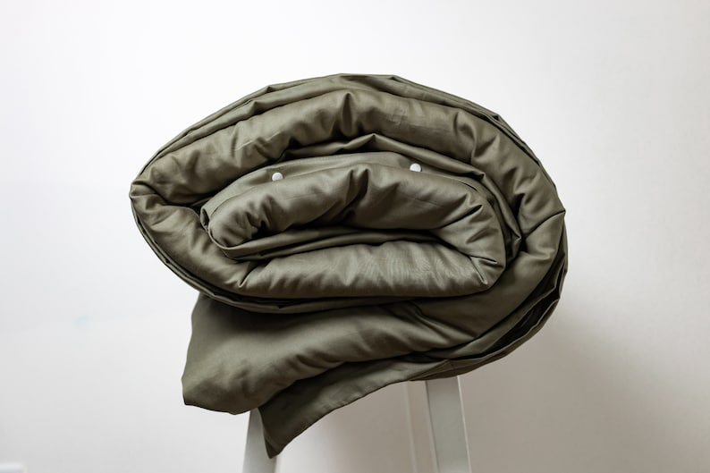 May include: A rolled up olive green duvet cover with white buttons.