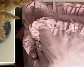 May include: A pair of pink pillowcases with ruffled edges. The pillowcases are made of a soft, smooth fabric.