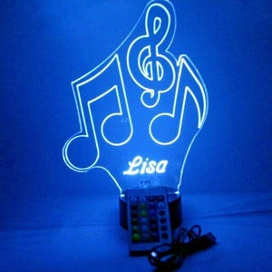 May include: A white acrylic night light shaped like a treble clef and musical notes with the name "Lisa" inscribed below. The light has a remote control with multiple color options.
