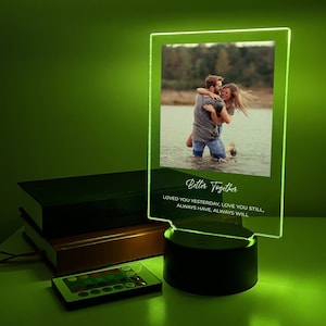 Peut inclure: Un cadre photo en acrylique transparent avec une base blanche présente une photo en noir et blanc d'un couple dans un lac. Le cadre porte une inscription blanche qui dit "Better Together Loved you yesterday, love you still, always have, always will".