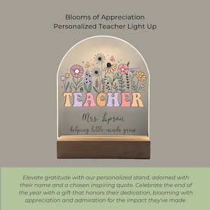 Op de afbeelding: Een gepersonaliseerde leraar-lamp met een bloemenontwerp. De lamp heeft het woord "TEACHER" in kleurrijke letters en de tekst "Mrs. Lipson helping little minds grow".