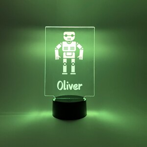 Könnte beinhalten: Ein grünes Nachtlicht mit einem weißen Roboter und dem Namen Oliver darauf.