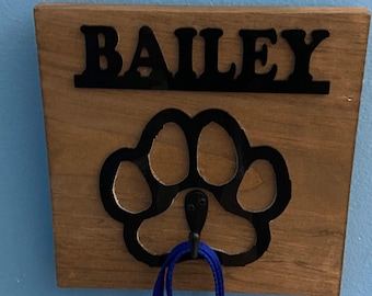 May include: Wooden dog leash hook with a black paw print design and the name "BAILEY" in black lettering.