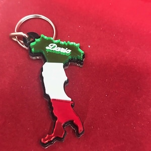 May include: A green, white, and red Italian-shaped keychain with the name "Daria" written on the top.