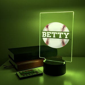 May include: A green acrylic night light with a white baseball and the name "BETTY" in white text. The light has a black base and comes with a remote control.
