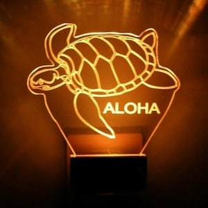 May include: A glowing orange night light shaped like a sea turtle with the word "ALOHA" underneath.