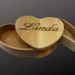 May include: A wooden heart-shaped box with a hinged lid. The lid is engraved with the name "Linda".