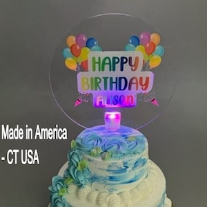 Könnte beinhalten: Ein transparenter Acryl-Kuchentopper mit einem bunten Ballon-Design und dem Text "Happy Birthday Alison". Der Topper hat ein Licht, das das Design beleuchtet.