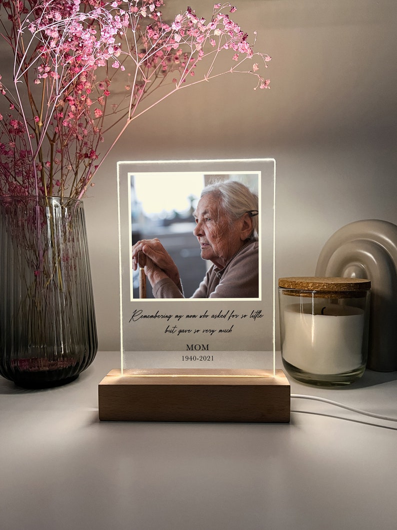 May include: A wooden light-up photo frame with a black and white photo of an older woman. The frame has a white background with the text "Remembering my mom who asked for so little but gave so very much MOM 1940-2021".