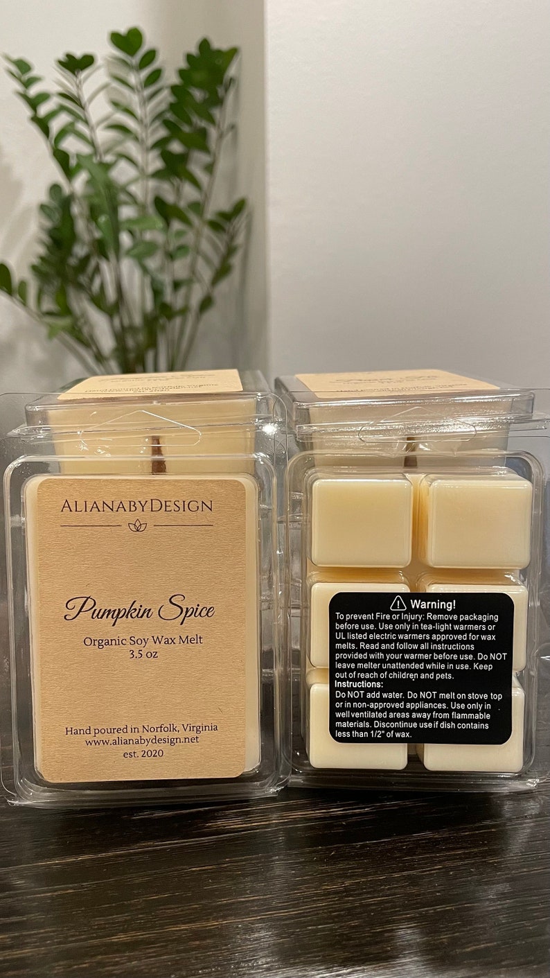 May include: Two clear plastic containers of soy wax melts, each containing four cubes of wax. The container on the left has a label that reads "ALIANABY DESIGN" and "Pumpkin Spice Organic Soy Wax Melt 3.5 oz". The container on the right has a label that reads "Warning!" and includes instructions for safe use.