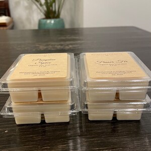 May include: Four stacks of organic soy wax melts in clear plastic containers. The top layer of each stack has a label with the text "ALLIANABYDESIGN" and the scent name. The scents are "Pumpkin Spice" and "Fraser Fir". Each stack is 3.5 oz.