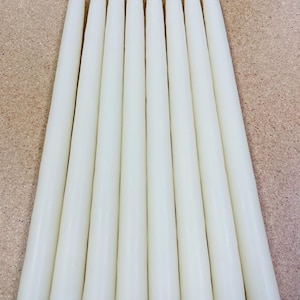 May include: A set of eight smooth, off-white taper candles arranged in a parallel vertical row. Each candle features a slender, cylindrical body that tapers slightly towards the top, ending in a pointed wick. The candles have a solid, matte finish.