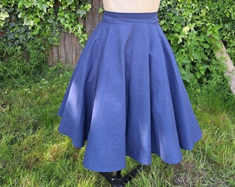May include: A full-circle skirt in a dark blue color. The skirt is made of a smooth, cotton fabric and has a simple, classic design.