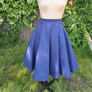 May include: A full-circle skirt in a dark blue color. The skirt is made of a smooth, cotton fabric and has a simple, classic design.