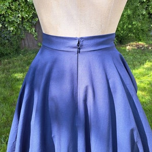 May include: A navy blue skirt with a full circle shape and a zipper closure in the back.