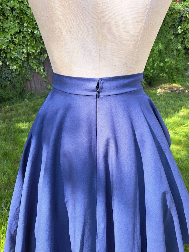 May include: A navy blue skirt with a full circle shape and a zipper closure in the back.