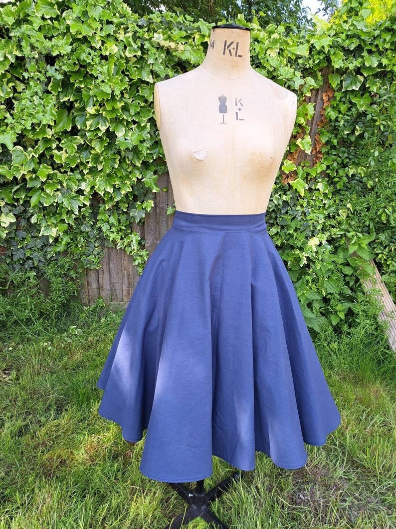 May include: A full-circle skirt in a dark blue color. The skirt is made of a smooth, cotton fabric and has a simple, classic design.