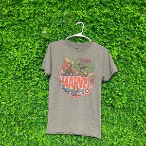 May include: A gray t-shirt with a graphic of Marvel superheroes surrounding the word "MARVEL" in red letters.