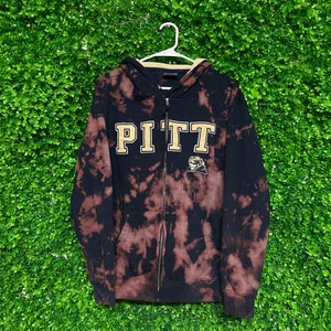 May include: Black and white tie-dye zip-up hoodie with the word "PITT" in gold lettering and a small gold mascot logo.
