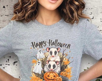 May include: A heather gray t-shirt with a Halloween-themed graphic. The design features two opossums, ghosts, pumpkins, and fall leaves. The words "Happy Halloween" are printed above the graphic in a script font.