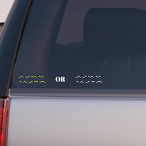 May include: A car window sticker featuring the words "SEE" and "OR" in braille. The word "SEE" is in yellow braille dots, and the word "OR" is in white braille dots. The sticker is on the rear window of a silver car.