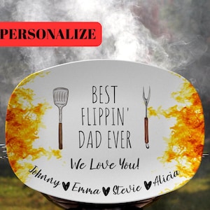 May include: White oval serving platter with a yellow and orange flame design. The platter has black text that reads "Best Flipping' Dad Ever! We Love You!" with the names "Johnny", "Emma", "Stevie", and "Alicia" written below.