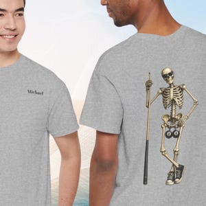 Peut inclure: Un t-shirt gris chiné avec le prénom Michael imprimé en noir sur la poitrine gauche. Le dos du t-shirt présente un motif de squelette portant des lunettes de soleil, tenant une queue de billard et portant des baskets noires avec des billes.