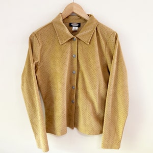 May include: A long-sleeved, yellow button-down shirt with a small, white polka dot pattern. The shirt has a collared neckline and a button-up front closure. The brand name "Crocker" is visible on the label.