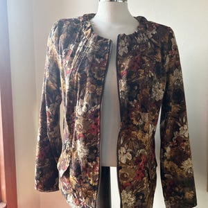 May include: A brown floral print jacket with a zipper closure. The jacket has a  pocket on the left side.