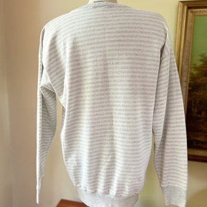 May include: A gray and white striped long-sleeve sweatshirt with a ribbed crew neck and cuffs.