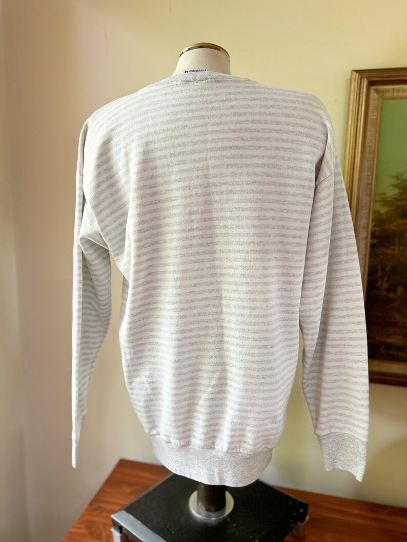 May include: A gray and white striped long-sleeve sweatshirt with a ribbed crew neck and cuffs.