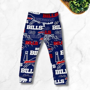 Könnte beinhalten: Dunkelblaue Leggings mit einem sich wiederholenden weiß-roten Muster des Buffalo Bills-Logos, dem Wort "BILLS" in fettem weißem und rotem Text, dem Wort "BUFFALO" in Weiß und "GO BILLS" in weißem Text, mit Bündchen an den Knöcheln und elastischem Bund.