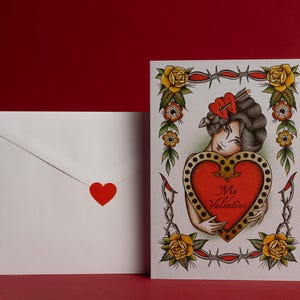 May include: A Valentine's Day card and envelope set. The card features a vintage tattoo-style illustration of a woman holding a heart with the words "My Valentine." The envelope has a red heart sticker.