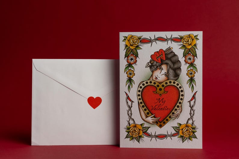 May include: A Valentine's Day card and envelope set. The card features a vintage tattoo-style illustration of a woman holding a heart with the words "My Valentine." The envelope has a red heart sticker.