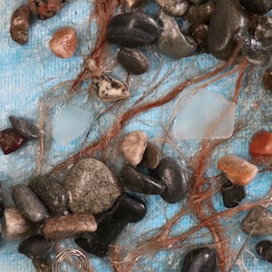 rocas del océano atlántico y vidrio marino con alambre de acero inoxidable y cordel sobre tablero de lona azul y blanco