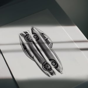 Puede incluir: Un boceto a lápiz detallado de un diseño de coche moderno y elegante. La ilustración, renderizada en escala de grises, muestra la forma aerodinámica, las ruedas y la estructura general del vehículo. La obra de arte está sobre una superficie blanca.