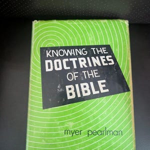 May include: A vintage book titled "Knowing the Doctrines of the Bible" by Myer Pearlman. The book has a green cover with white concentric circles and a black rectangle with white text. The book is in good condition.