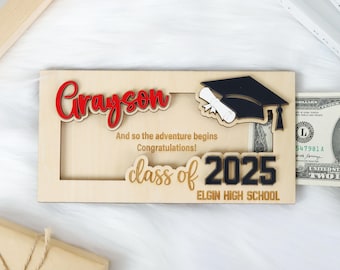 May include: Wooden graduation money holder with a red and white "Grayson" name cutout, a black graduation cap, and the text "And so the adventure begins Congratulations! class of 2025 ELGIN HIGH SCHOOL".